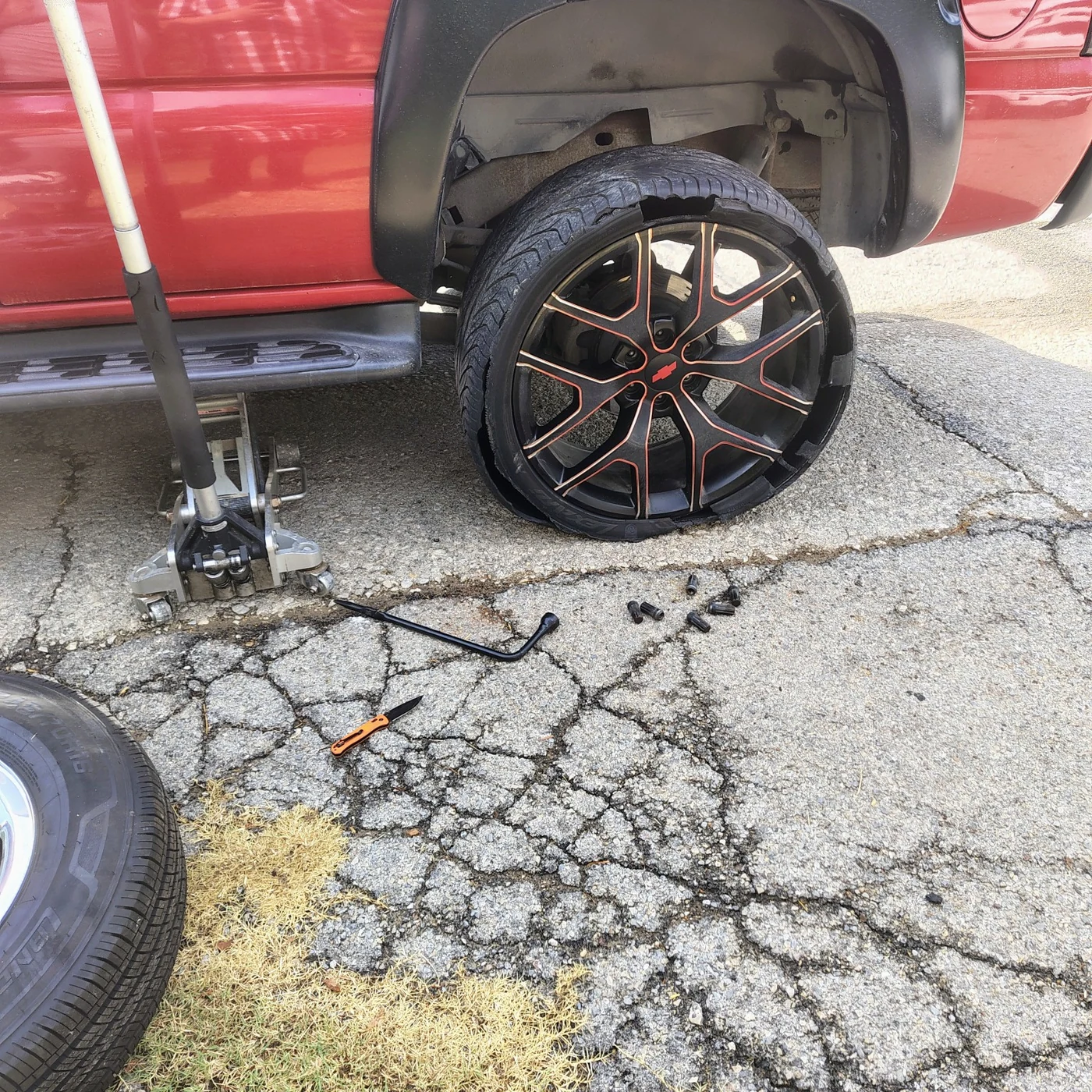 Damaged tire on a red pickup before roadside assistance in Hutchins