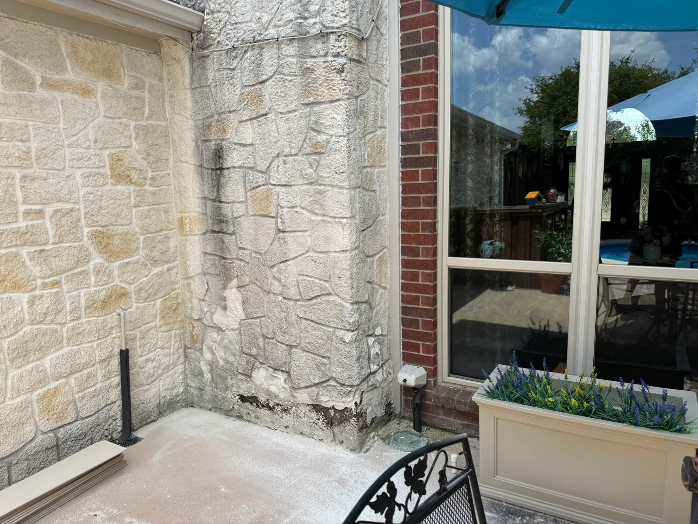 Exposed stone wall beside a patio window before the Plano siding project